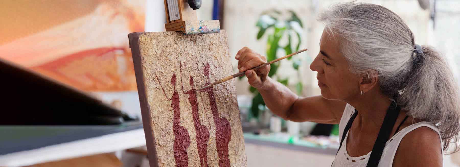 Se muestra una mujer mayor pintando un cuadro Se muestra una mujer mayor pintando un cuadro