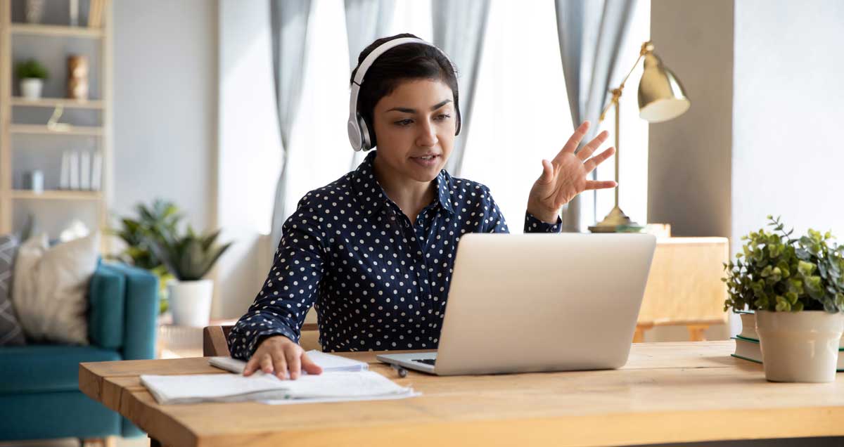 Se muestra una mujer sentada teniendo una videollamada en su laptop